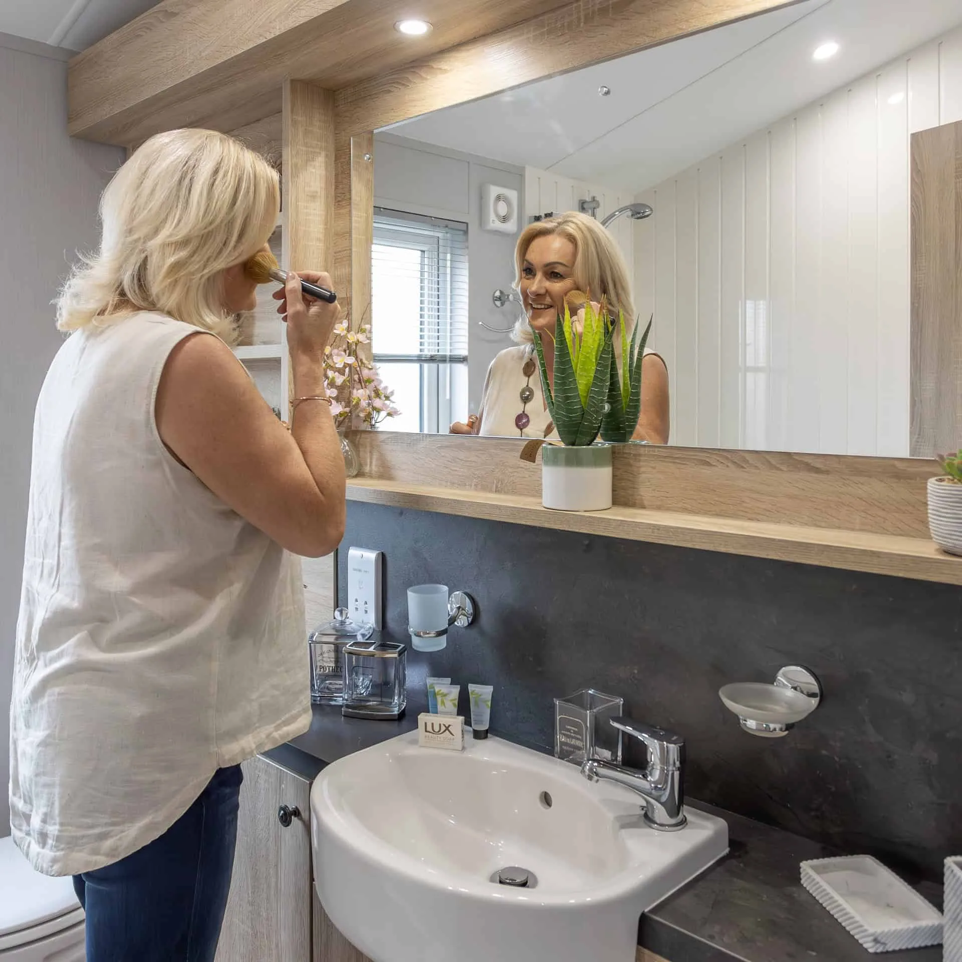 Woman doing her makeup in the modern bathroom of a Heathergate lodge
