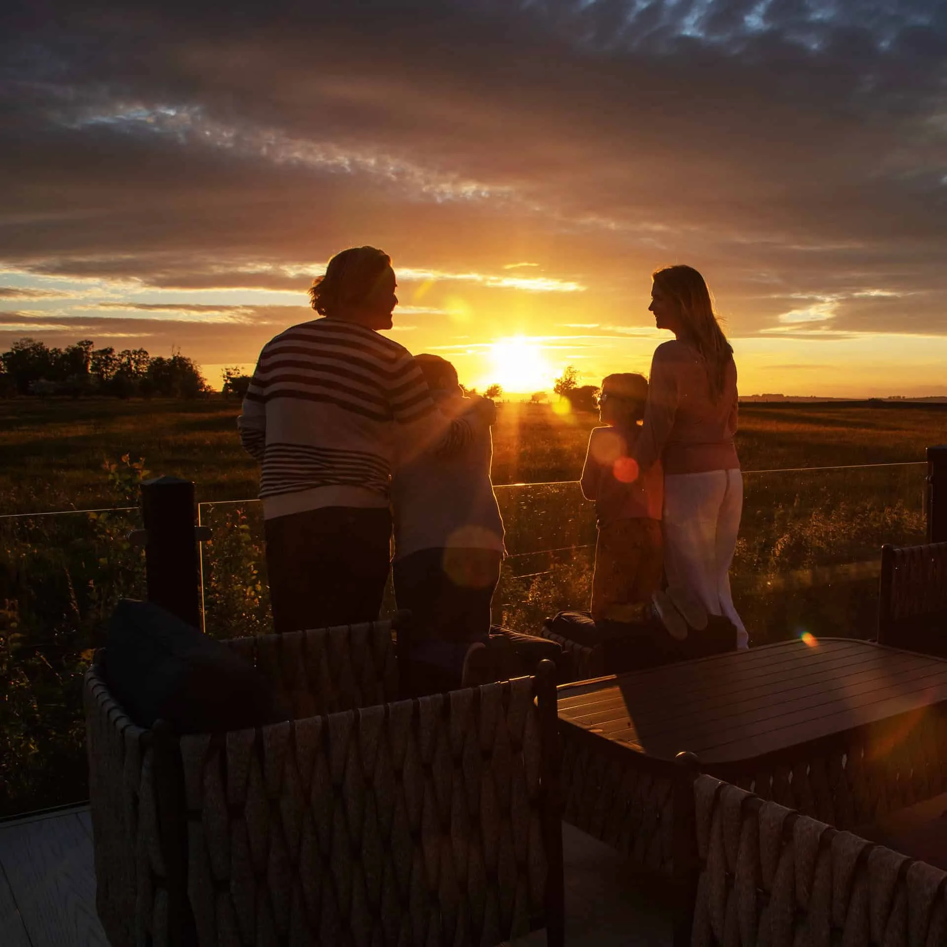 Couple watching the sunset from the balcony of a luxury lodge at Heathergate